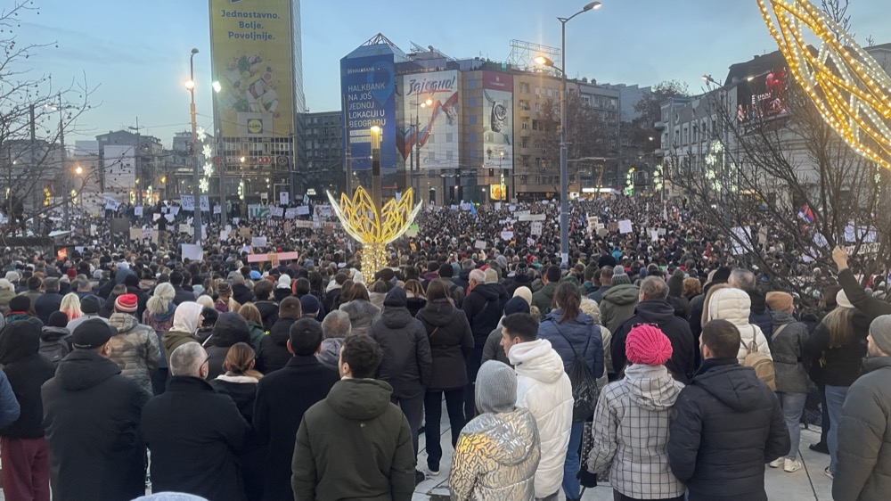 Ноћни протест на Тргу Славија у Београду, велика маса људи и српска застава.